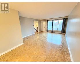 A spacious room with wooden flooring and a large window.