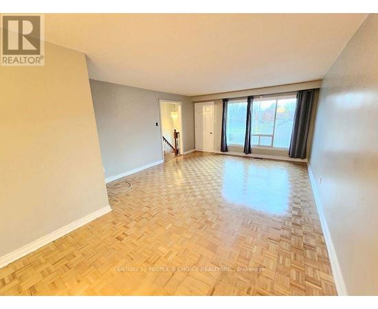 A spacious room with wooden flooring and a large window.