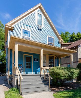 a blue house with a porch and stairs