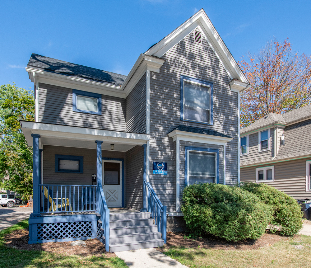 A grey house with a blue door and a small porch.