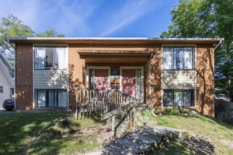 A brown house with a white car parked in front.