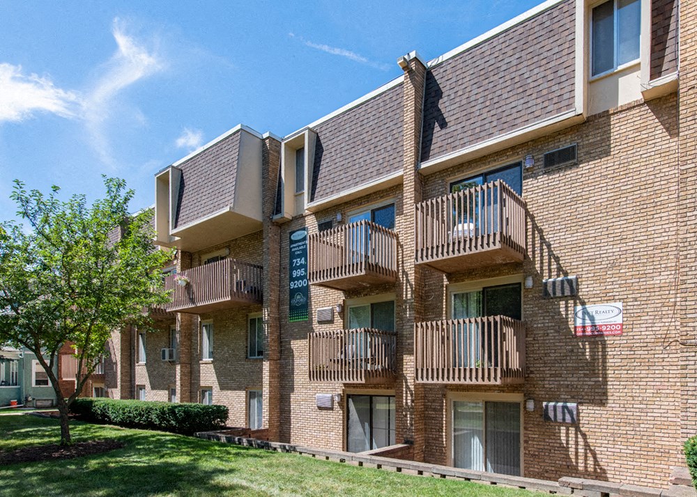 a brick apartment building with balconies and trees