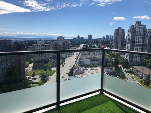 A view from a balcony overlooking a city street and buildings.