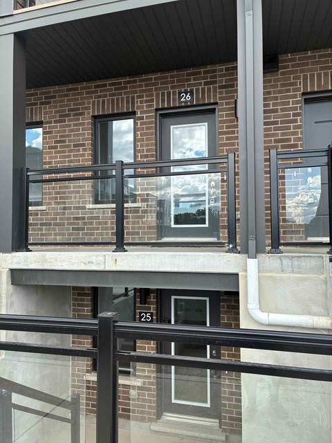 A balcony with black railings and windows numbered 25 and 26.