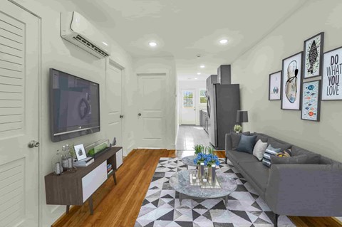 A living room with a grey couch, a coffee table, and a TV on the wall.