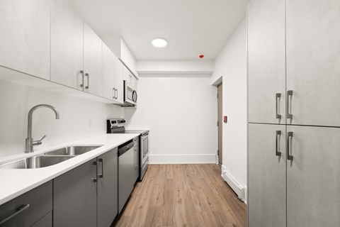 A kitchen with white cabinets and a wooden floor.