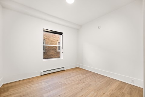 A room with a window and wooden flooring.