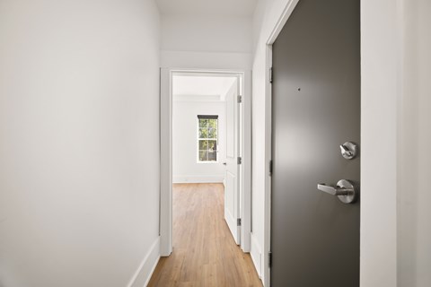 A hallway with a grey door and a white door on the other side.