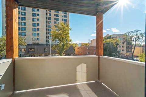 A balcony with a sunny sky and buildings in the background.