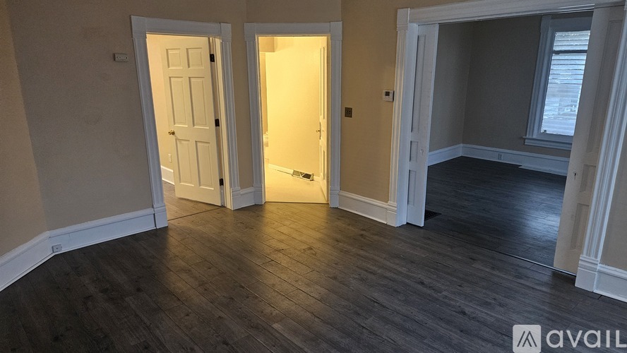 A room with wooden floors and three doors.