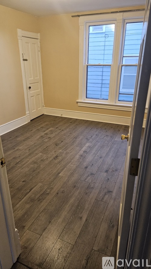 A room with wooden flooring and a window with blinds.