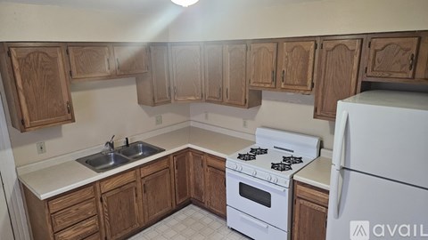 A kitchen with wooden cabinets and a white stove top oven.