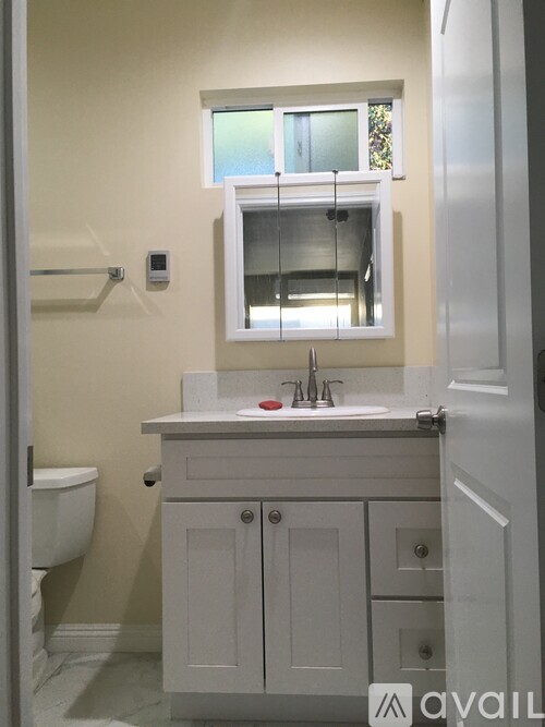 A bathroom with a white sink and a window above it.