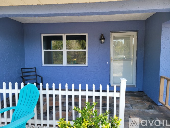 A blue house with a white picket fence and a green chair.