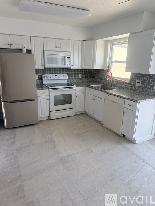 A kitchen with white cabinets and a tiled backsplash.