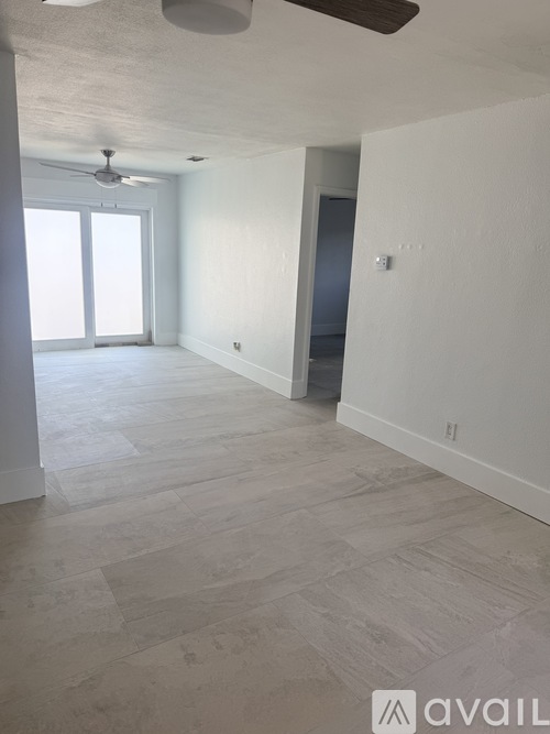 A spacious room with a ceiling fan and light, and a door on the right.