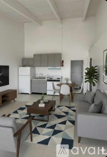 A living room with a grey couch, a coffee table, and a kitchen in the background.