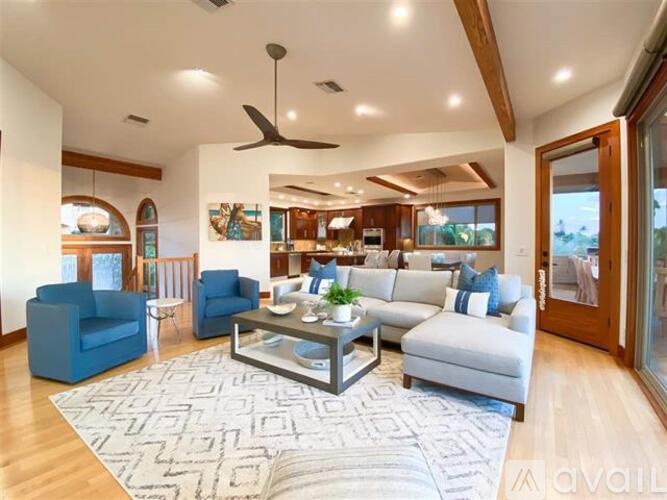 A spacious living room with a large rug and a ceiling fan.