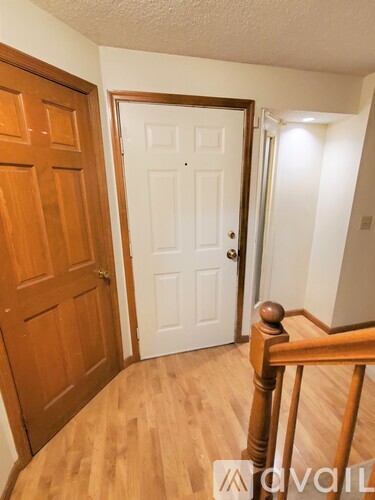 A hallway with a white door and a wooden floor.