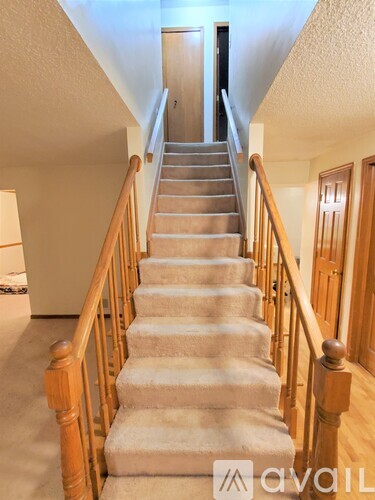 A staircase with wooden balusters and beige carpeted steps.