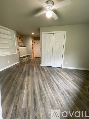 A room with a ceiling fan and wood flooring.
