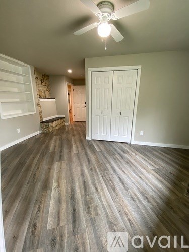 A room with a ceiling fan and wood flooring.