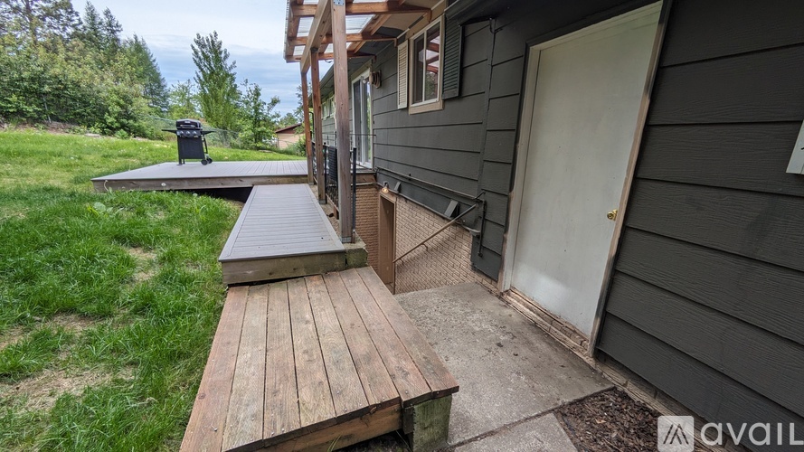 A wooden deck leads to a house with a white door.