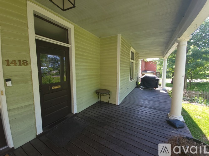A porch with a black door and a bench under a pergola.