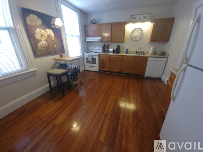 A kitchen with wooden floors and a white refrigerator.