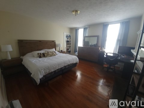 A bedroom with a large bed and a desk with a chair.