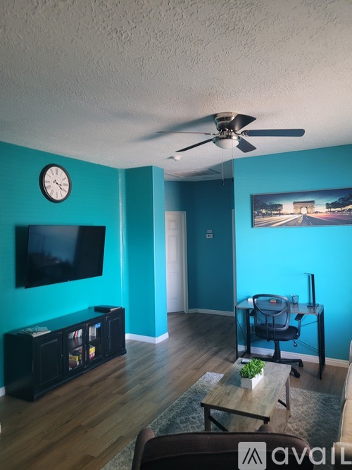 A living room with a television, a clock, and a blue wall.