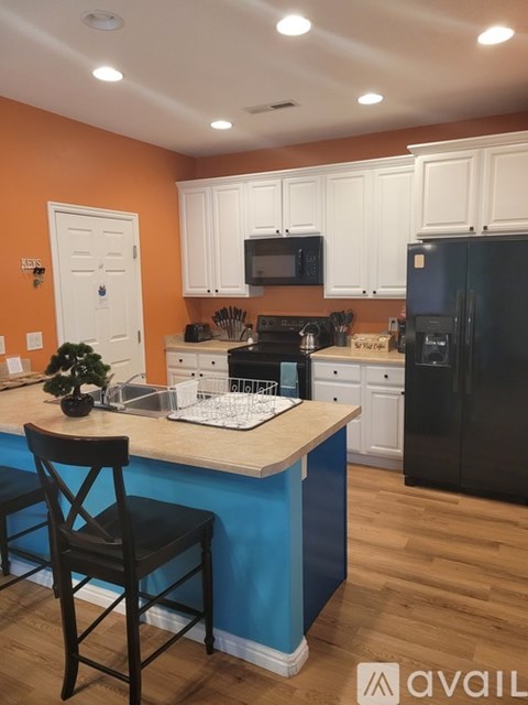 A kitchen with a black refrigerator and white cabinets.