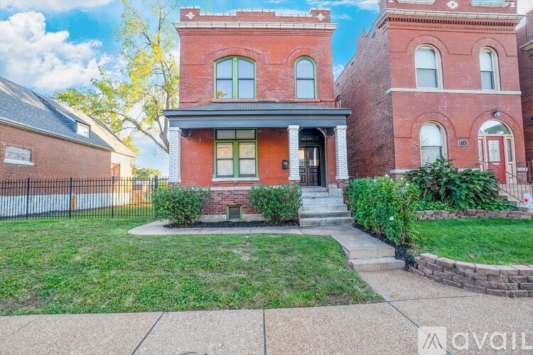 A red brick house with a green door and a small front yard.