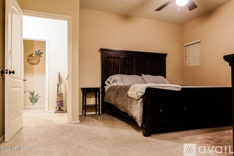 A bedroom with a bed, a small table, and a door leading to a cave.