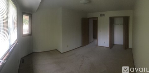 A spacious room with a window on the left side and a carpeted floor.