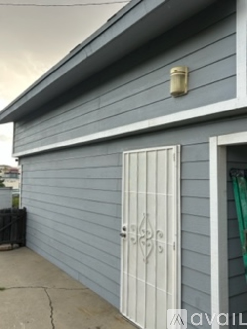 A grey house with a white door and a window.
