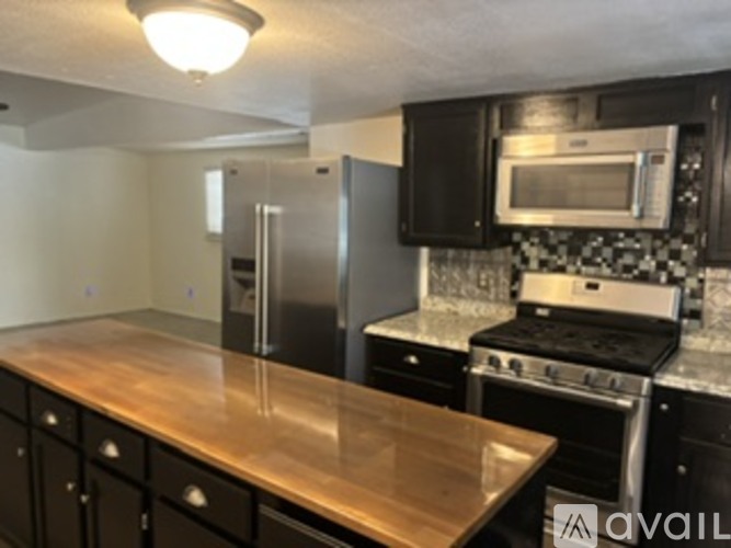 A kitchen with a stove, sink, and cabinets.
