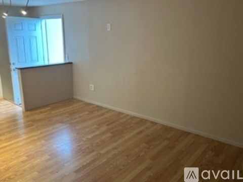 A room with wooden flooring and a door leading to another room.