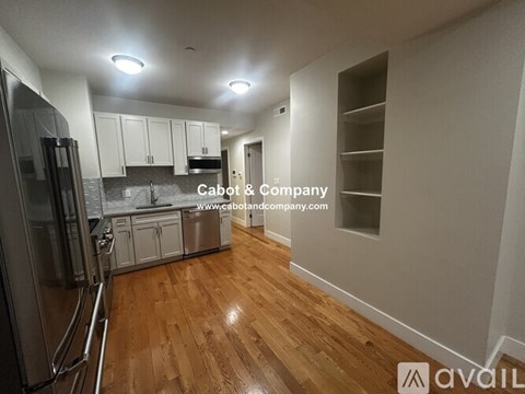 A kitchen with wooden floors and white cabinets is available for rent.