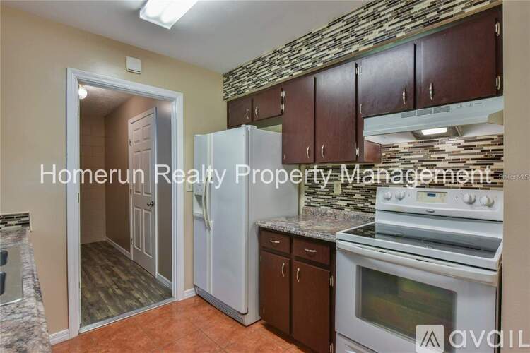 A kitchen with a stone backsplash and a refrigerator with the door open.