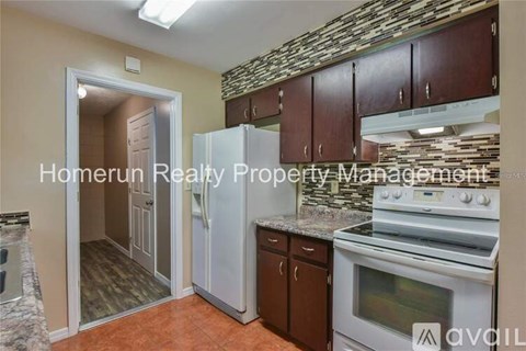 A kitchen with a stone backsplash and a refrigerator with the door open.