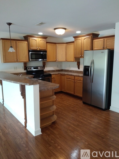 A kitchen with wooden cabinets and a stainless steel refrigerator.
