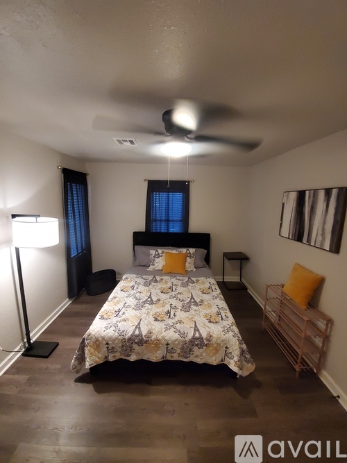 A bedroom with a bed, a ceiling fan, and a nightstand with a lamp.