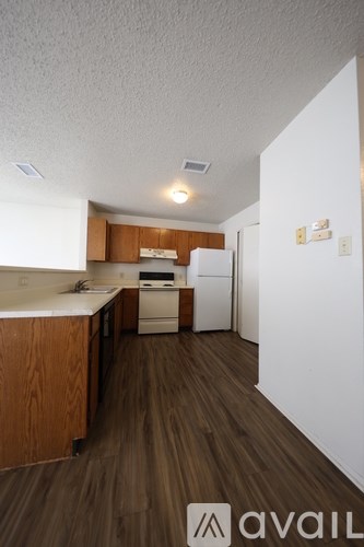 A kitchen area with wooden floors and white appliances.