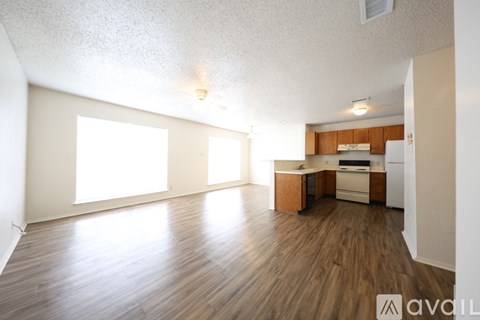A spacious living room with a kitchenette in the background.