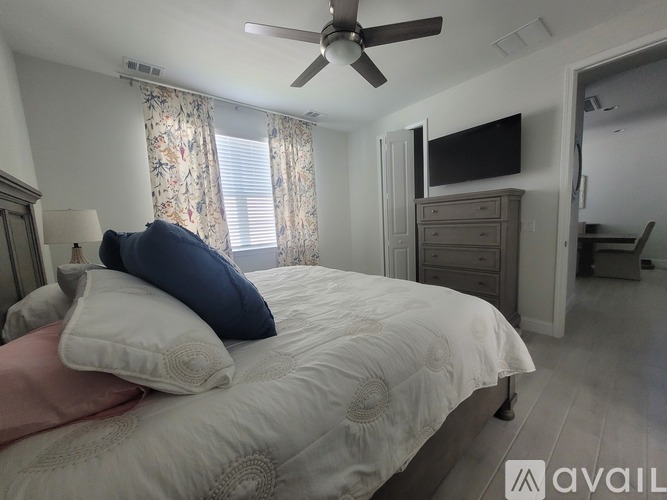 A bedroom with a large bed and a ceiling fan.