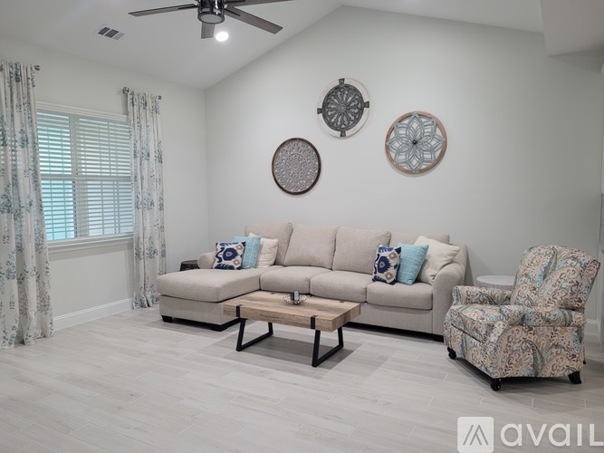 A living room with a beige couch, a patterned chair, and a coffee table.
