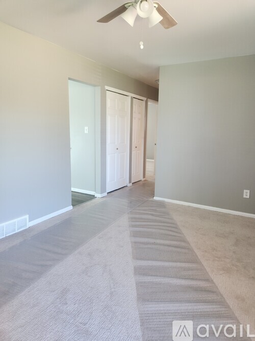 A room with a carpeted floor and a ceiling fan.