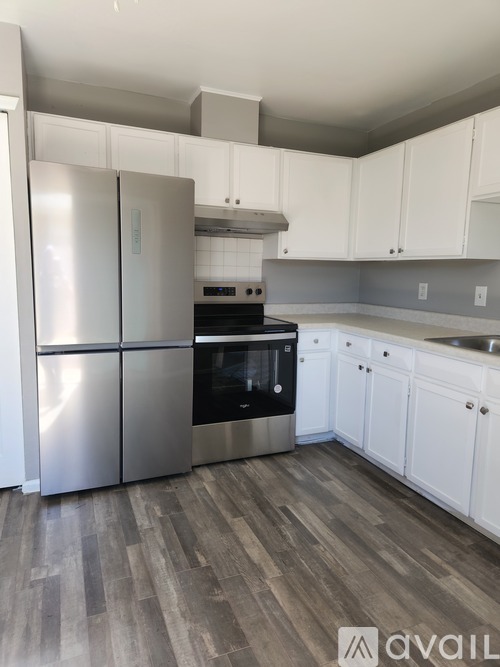 A kitchen with a stainless steel refrigerator and wooden flooring.