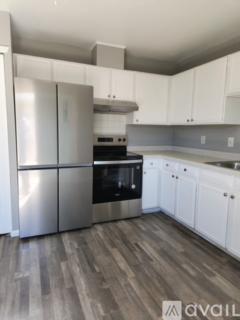 A kitchen with a stainless steel refrigerator and wooden flooring.